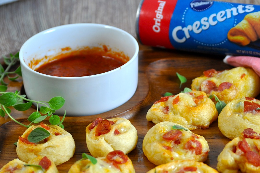 Finger Food Appetizers Close Up of a Cutting Board with Pepperoni Pinwheels On Top and a Ramekin of Marinara Sauce