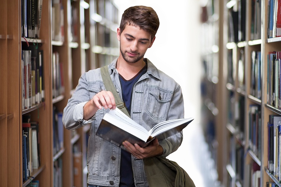 Quotes About New Beginnings for Students Male Student Standing in a Library Reading a Book