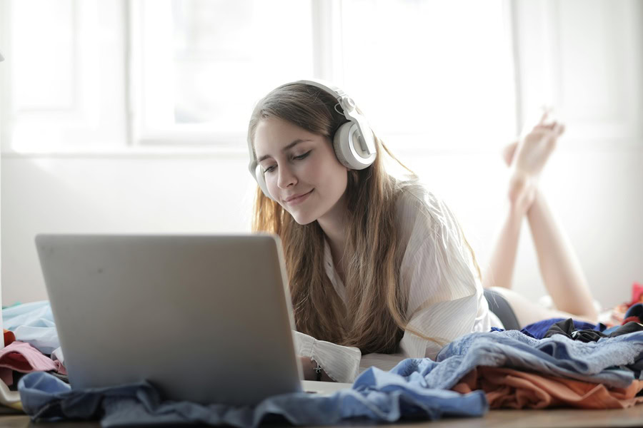 Netflix Shows Best Shows to Watch for All Ages a Woman Laying on a Bed Watching Something on Her Laptop While Wearing Headphones