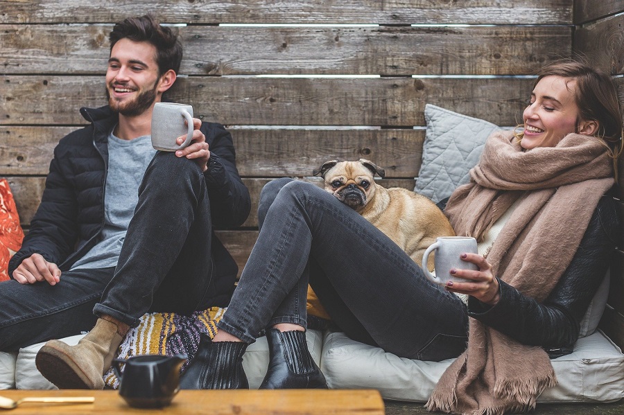Romantic Valentine's Day Quotes for Her Couple Sitting Together Bundled Up in Jackets with a Pug