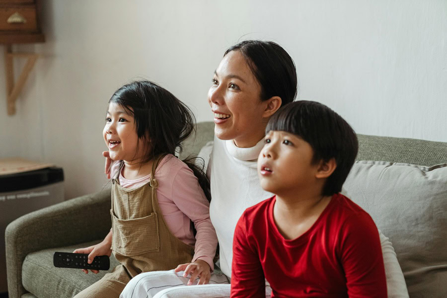 Family Friendly Movies to Watch at Home a Mom and Her Daughter and Son Watching TV Together on a Sofa