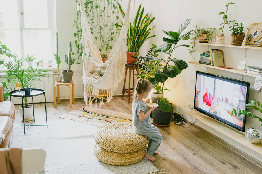 Family Friendly Movies to Watch at Home a Little Girl Sitting Down on a Chair in a Living Room Watching TV