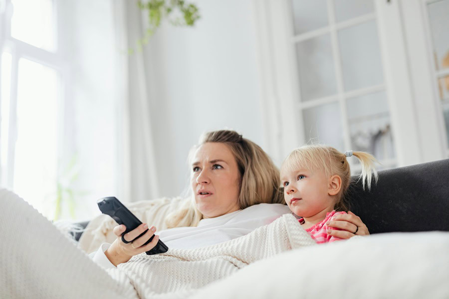 Family Friendly Movies to Watch at Home a Mom and Her Daughter Sitting on a Couch Watching TV Together