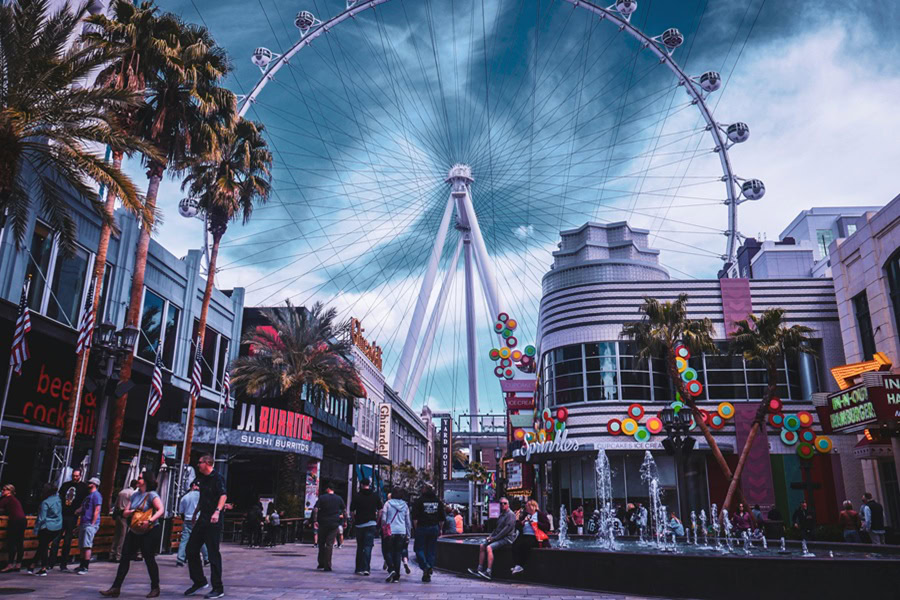 Free Things to Do in Las Vegas for Couples View of a Ferris Wheel in Las Vegas with Buildings in Front and People Walking Around