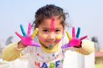 Quotes for Kids to Motivate Them a Young Girl Posing with Her Hands Up and Covered in Bright Paints