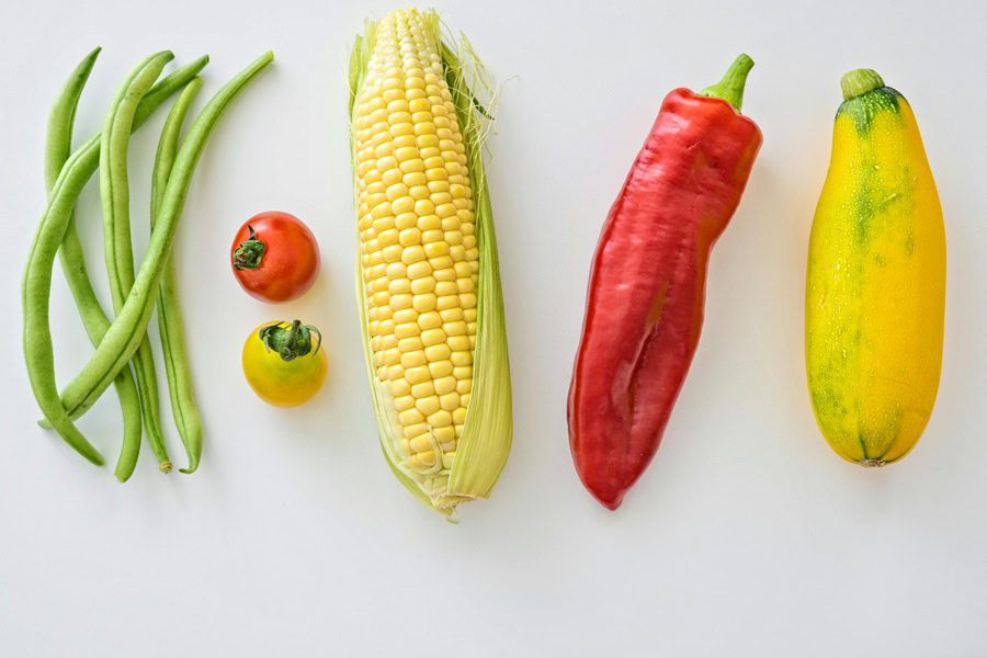 Vegetarian Party Recipes for a Crowd Green Beans, Tomatoes, Corn, Peppers and Squash on a White Surface