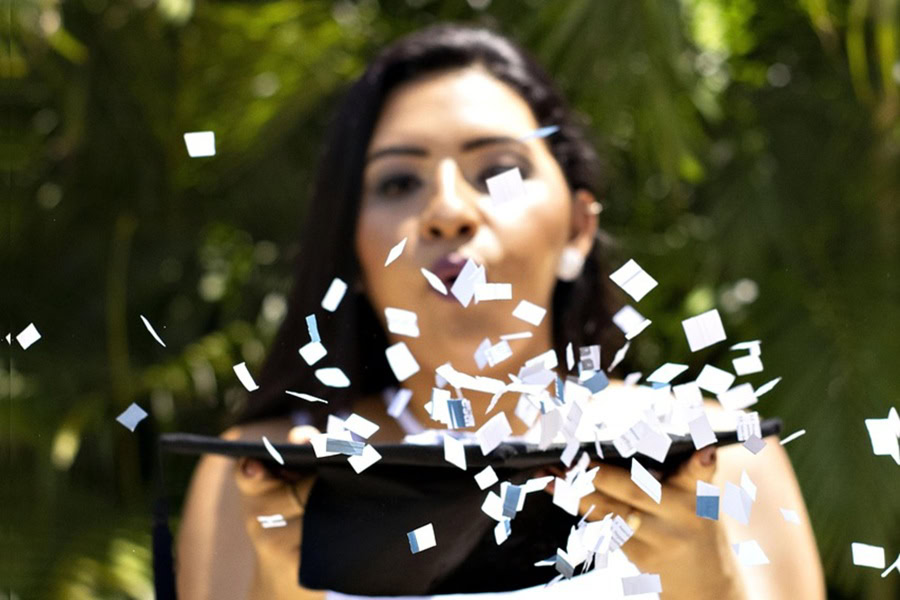 High School Graduation Party Foods a Female Student Holding Up Her Graduation Cap Blowing Confetti Off the Top Toward the Camera