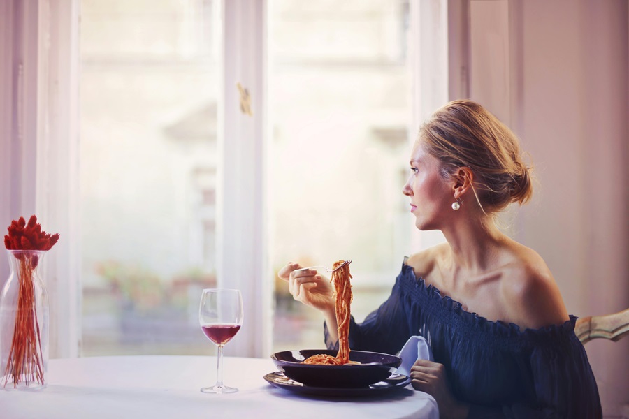 Must Have Red Wine Reduction Recipes a Woman Sitting at a Table Eating Spaghetti with a Glass of Red Wine