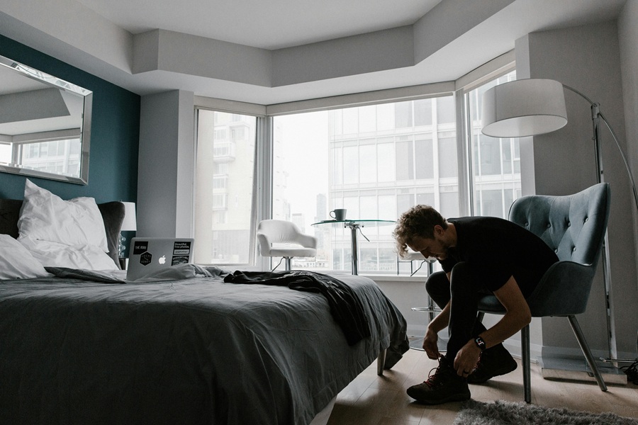 How to Start Your Day a Man Sitting on a Chair in His Room Bending Over and Tying His Shoe