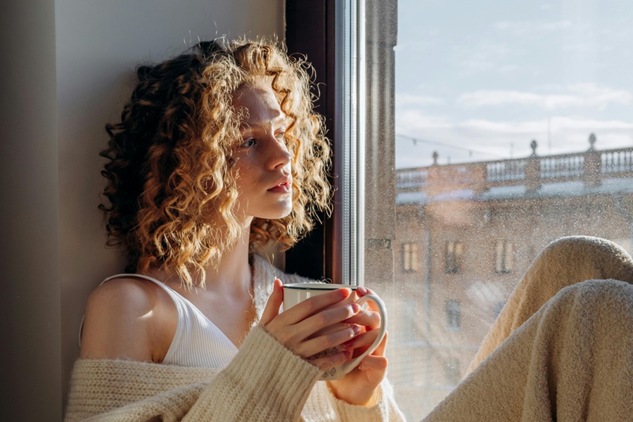 How to Start Your Day a Woman Sitting in Her Window, Looking Out at the Morning Drinking Something from a Cup