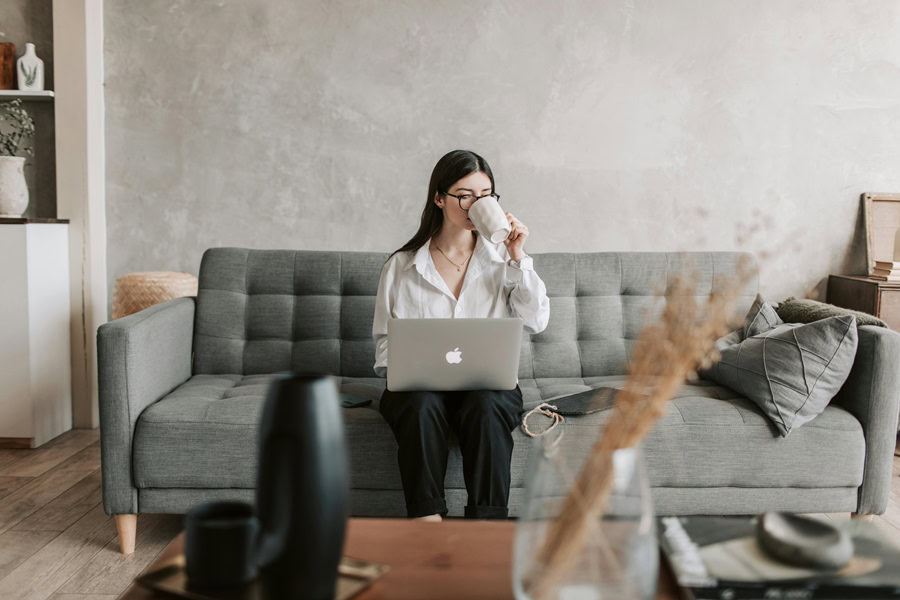 Powerful Quotes For Entrepreneurs a Woman Sitting on a Couch Drinking Coffee and Working on a Laptop