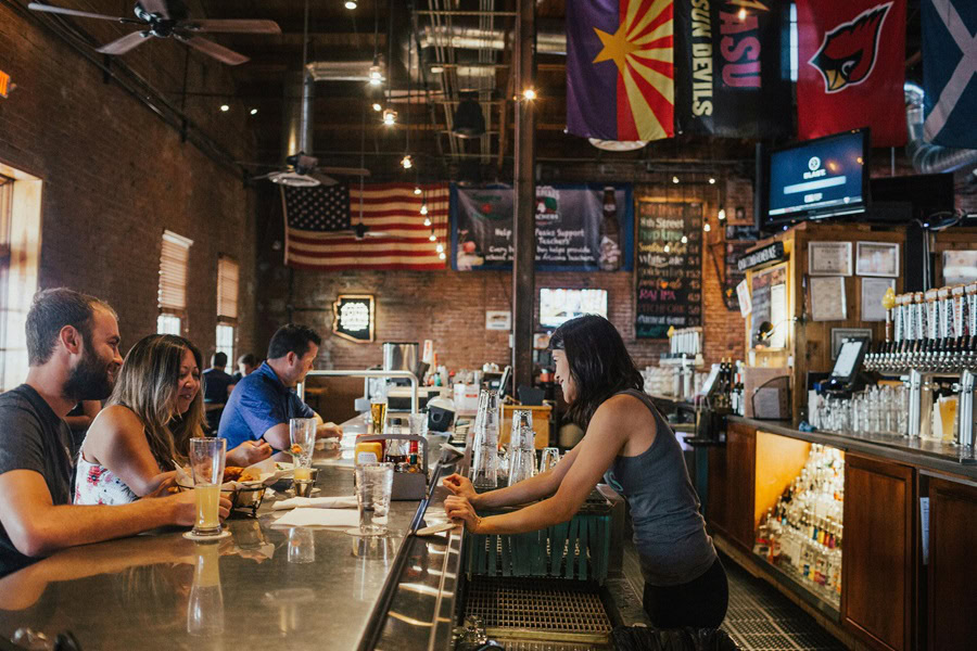 Best Dive Bars in San Diego a Woman Behind a Bar Serving People Beer and Cocktails