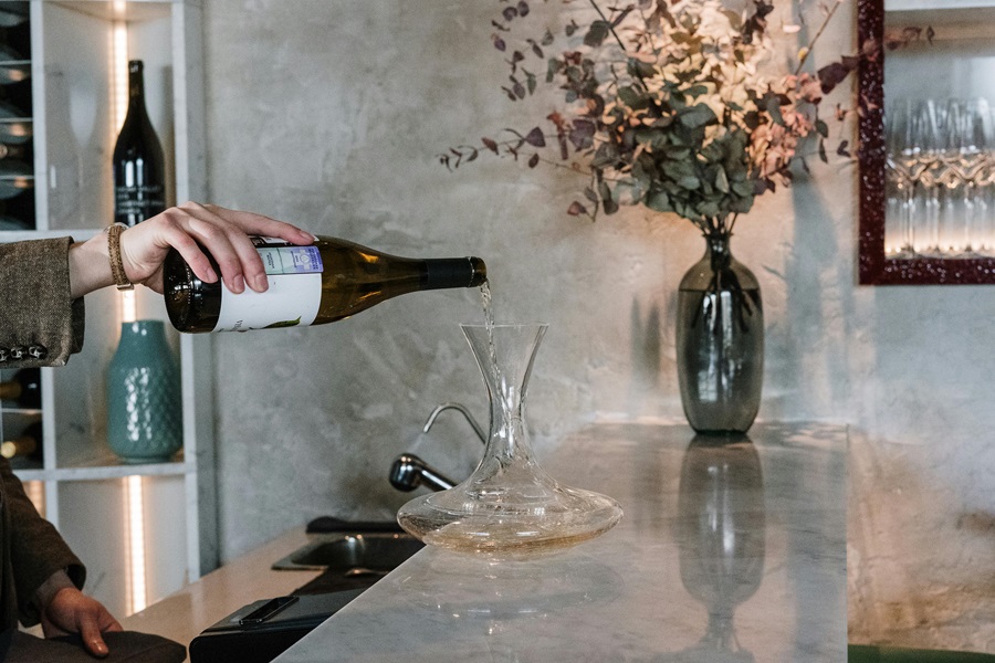 24 Wine Tasting Rooms in Downtown Napa a Person Pouring a Glass of Wine on a Marble Countertop with a Vase of Flowers in the Background