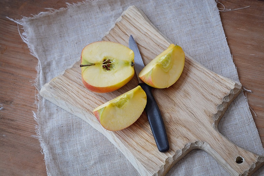 Best Snacks to Eat at Night for Weight Loss An Apple Cut in Half and One Half Cut in Half Again on a Wooden Cutting Board