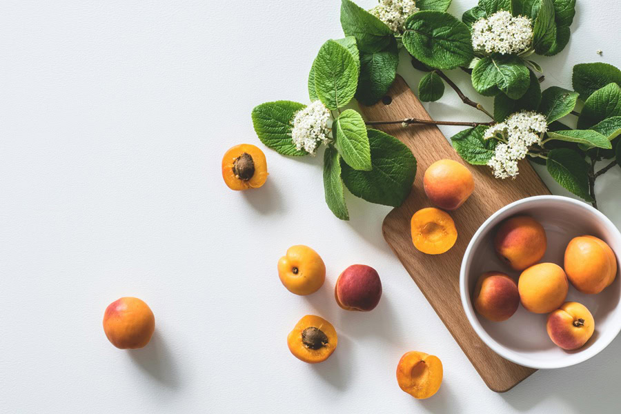 Clean Eating Tips for Beginners Peaches on a Cutting Board with Sprigs of Leaves from a Tree