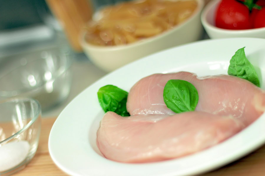 Clean Eating Tips for Beginners Two Raw Chicken Breast on a White Plate in a Kitchen