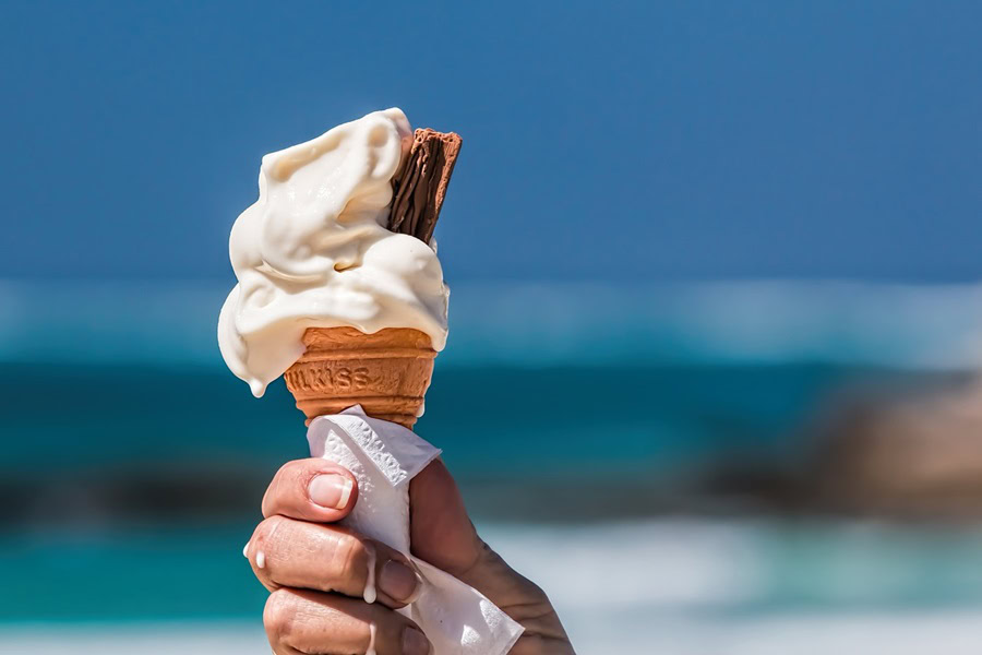 Best Summer Captions for Instagram Close Up of a Person's Hand Holding a Melting Ice Cream Cone with a Piece of Chocolate in it