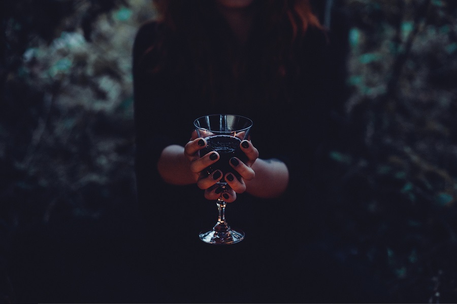 Halloween Virgin Party Drinks Close Up of a Woman Holding a Goblet of Liquid in a Forest