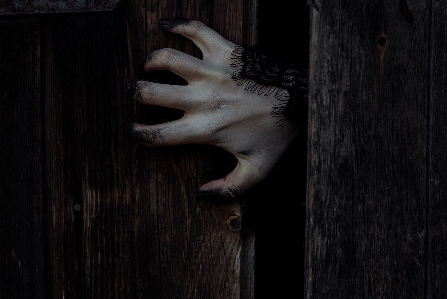 Best Scary Halloween Movies of all Time Close Up of a Scary Hand Reaching Out From Behind a Door