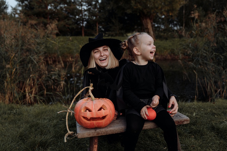 Halloween Games for Kids Mom and a Little Girl Sitting on a Bench Outside Dressed in Black with Pumpkins