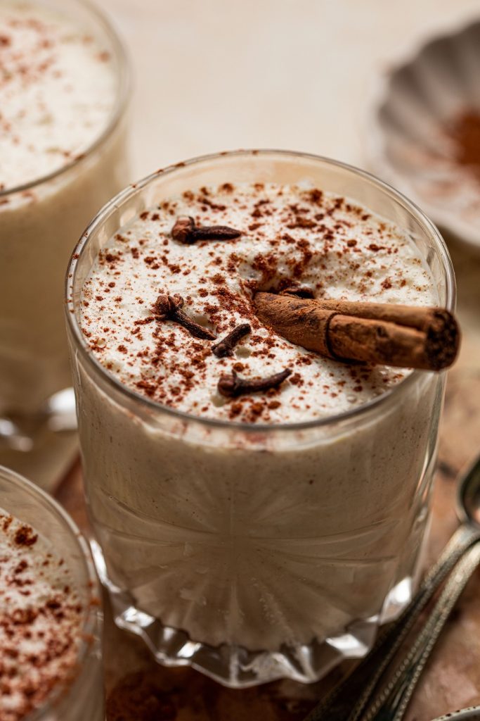 Homemade Spiked Eggnog with Bourbon Recipe Angled View of a Glass of Eggnog with a Cinnamon Stick Inside