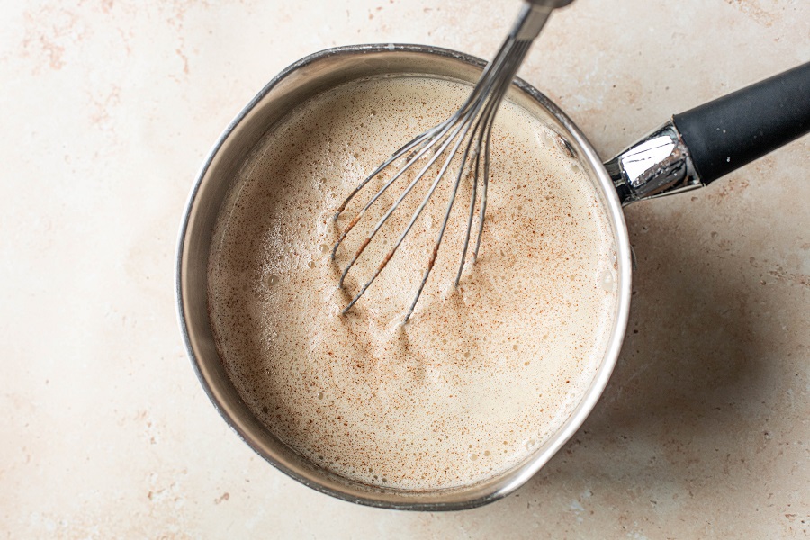 Homemade Spiked Eggnog with Bourbon Recipe Overhead View of a Pot with Custard and Meringue Mixed Together