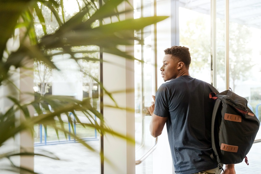 Dorm Room Decor College Student Walking Out of a Building with His Backpack