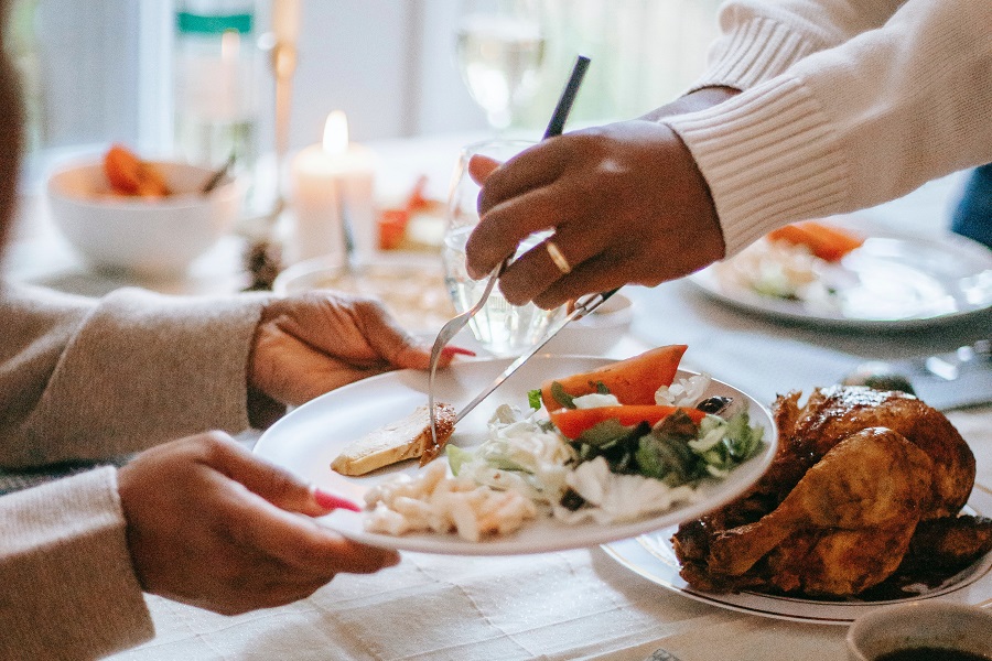 Thanksgiving Dinner Recipes for a Feast Close Up of One Person Putting Food on a Plate Being Held by Another Person