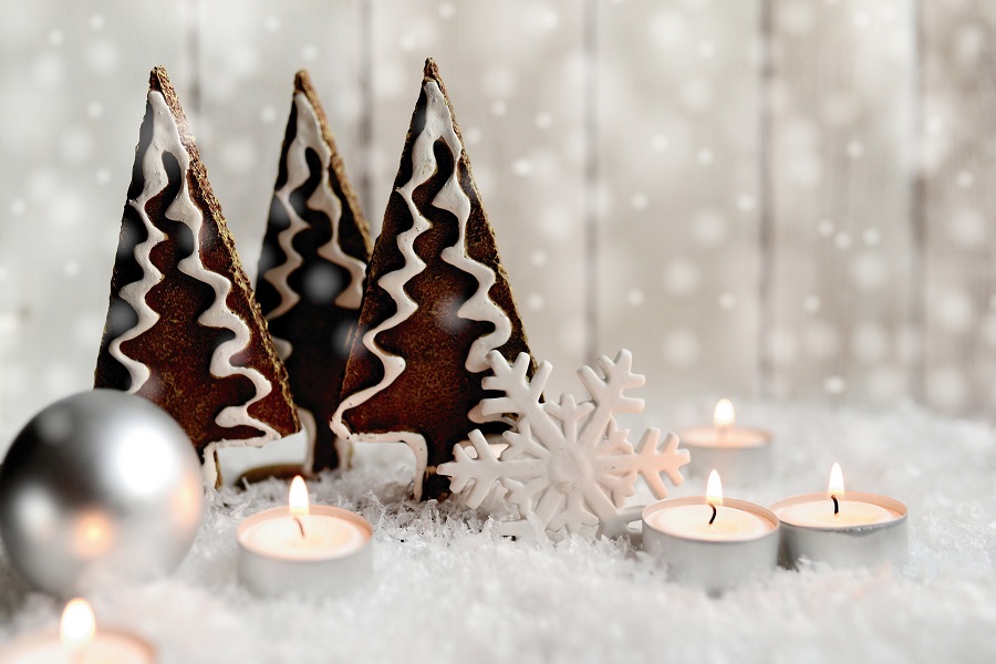 DIY Christmas Decor Ideas Tealight Candles Sitting Next to Three Christmas Tree Gingerbread Cookies With Snow on the Surface