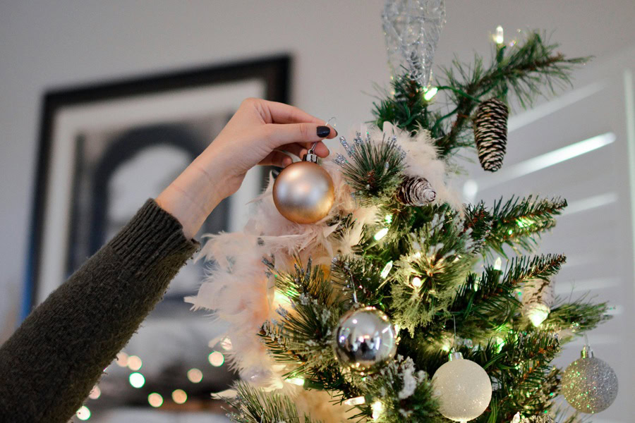 DIY Christmas Tree Close Up of a Person Putting an Ornament on a Christmas Tree