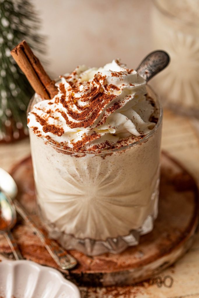 Bourbon Eggnog Recipe Close Up of a Glass of Eggnog Topped with Whipped Cream and Cinnamon