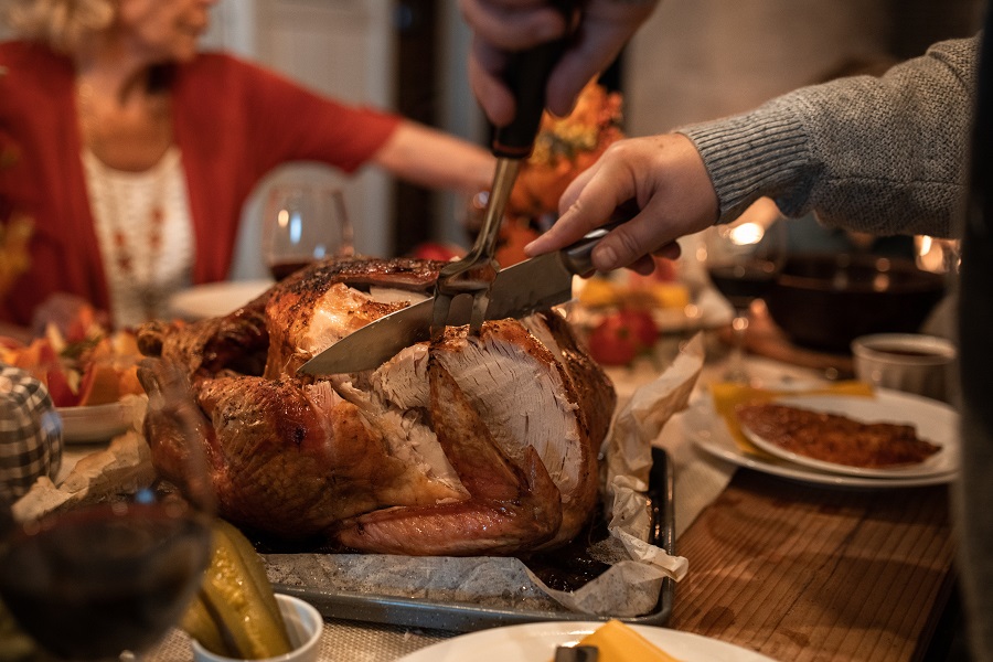 Funny Thanksgiving Clapbacks Close Up of a Person Carving a Turkey with People Sitting Around the Table in the Background