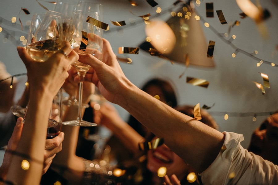 New Years Eve Outfits Close Up of People Raising Cocktail Glasses with Gold Confetti Falling Around Them