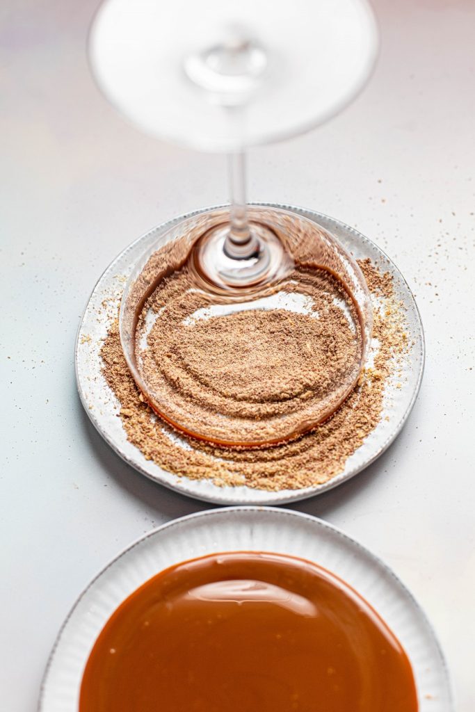 Pumpkin Spice Mocktail Glass Being Dipped into Graham Cracker and Chocolate Mixture