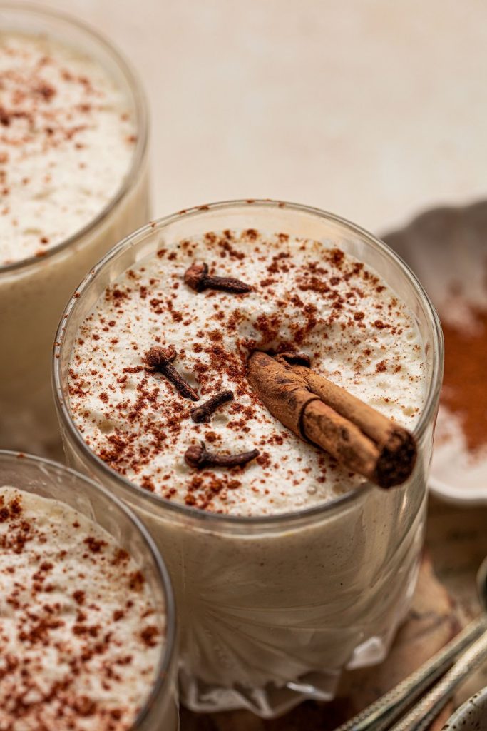 Bourbon Eggnog Recipe Angled View of a Glass of Eggnog with a Cinnamon Stick Inside