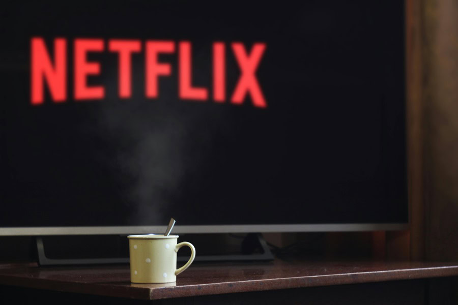 Best Stupid Movies to Watch on Netflix a TV with Netflix on the Display and a Cup of Tea in Front of It