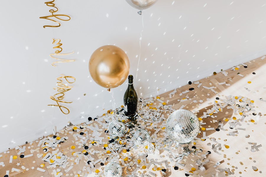 DIY New Years Eve Decor  a Bottle of Champagne on the Floor Next to Golden Confetti and a Disco Ball