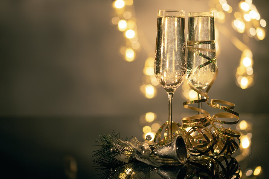 DIY New Years Eve Decor  Two Champagne Flutes Filled with Champagne Next to Gold Glitter and Confetti