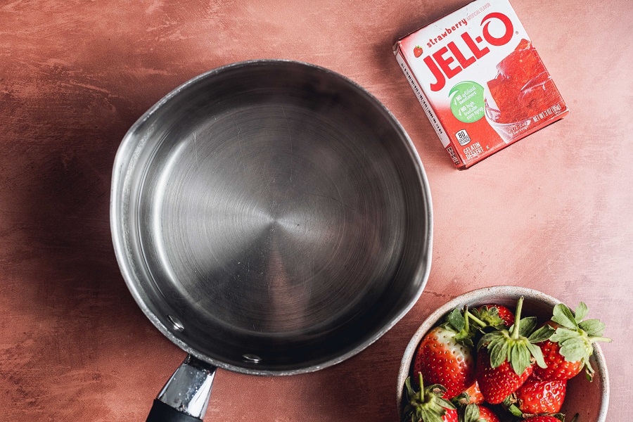 Easy Santa Hat Jello Shot Recipe A Silver Pot Next to a Small Bowl of Fresh Strawberries and a Box of Red Jell-O