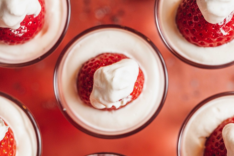 Easy Santa Hat Jello Shot Recipe Overhead View of a Bunch of Jello Shots Garnished with a Strawberry and Whipped Cream