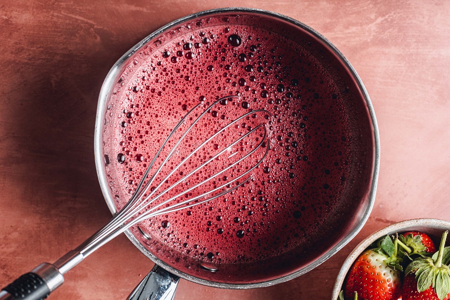 Easy Santa Hat Jello Shot Recipe a Bowl with Jello Mixture Being Whisked with a Metal Whisk