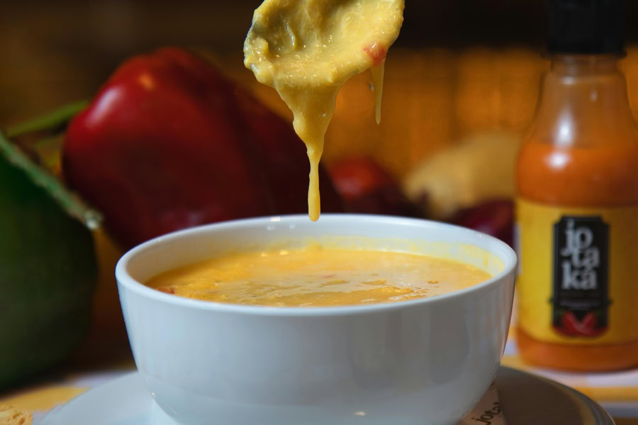 Beer Dip for Pretzels Cheese Dip Dripping from a Spoon Hovering Above a Small Bowl of Cheese Dip