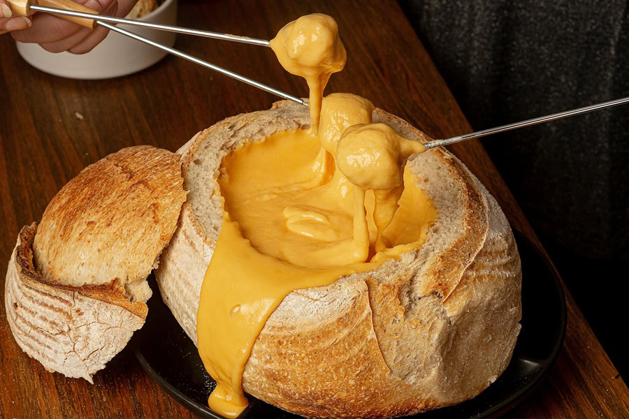 Beer Dip for Pretzels Cheese Fondue in a Bread Bowl with Two Sticks of Food Covered in Cheese