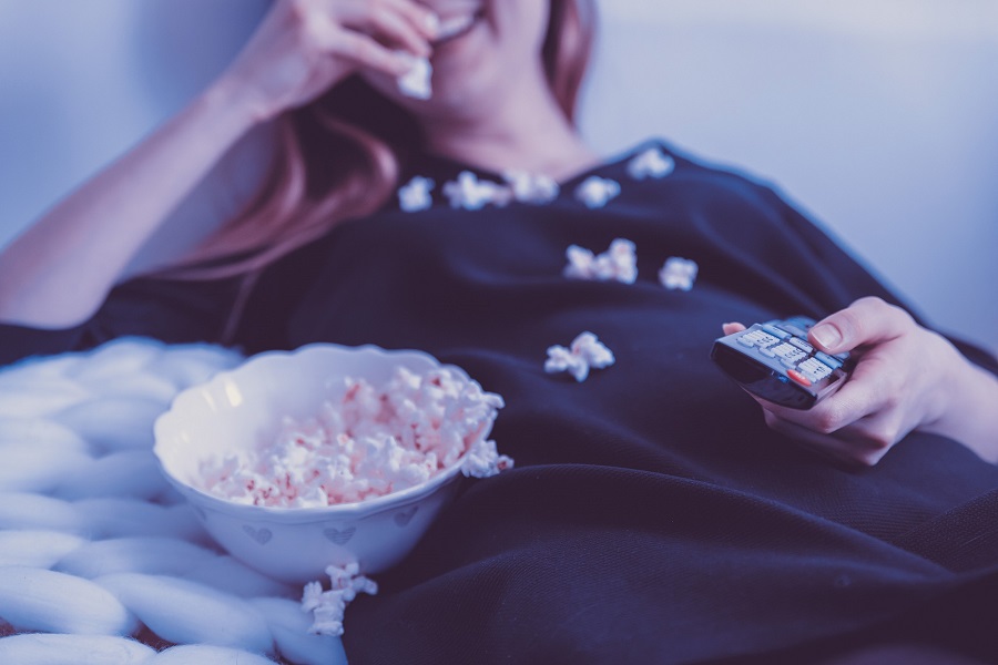 Netflix Shows You May Have Missed Close Up of a Woman Laying Down Under a Blanket Holding a Remote Eating Popcorn with Popcorn Spilled All Over Her Chest
