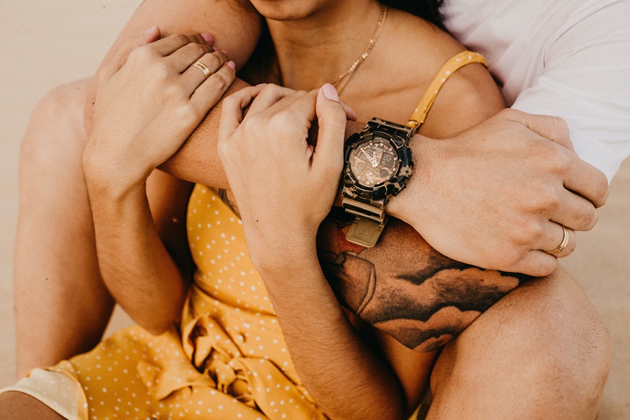 Valentines Photoshoot Ideas Close Up of a Man's Arm Wrapped Around a Woman Who is Holding Onto His Arm