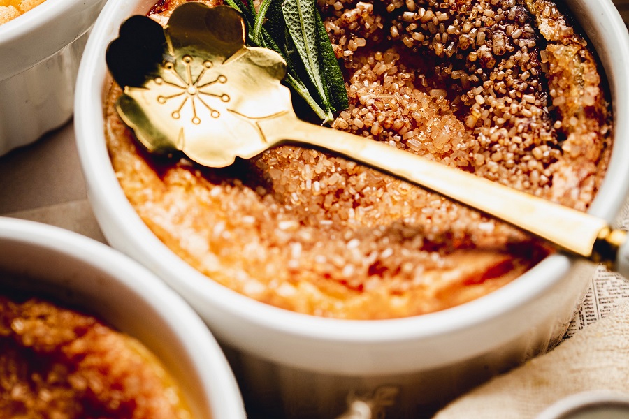Easy No Torch Creme Brulee Recipe Close Up of a Ramekin of Creme Brulee with a Decorative Spoon Lying ontop