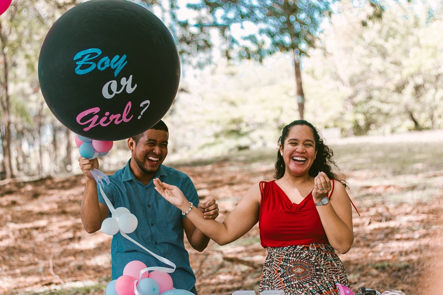 Gender Reveal Ideas for Spring a Couple Holding a Black Balloon That Says Boy or Girl