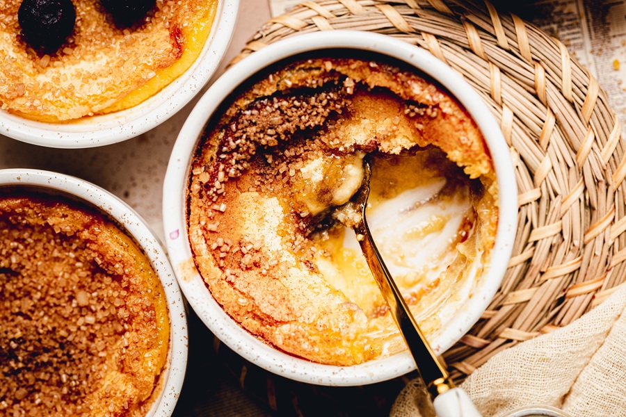 Recipe for Easy Creme Brulee Overhead View of a Cracked Creme Brulee with a Spoon and Custard Missing