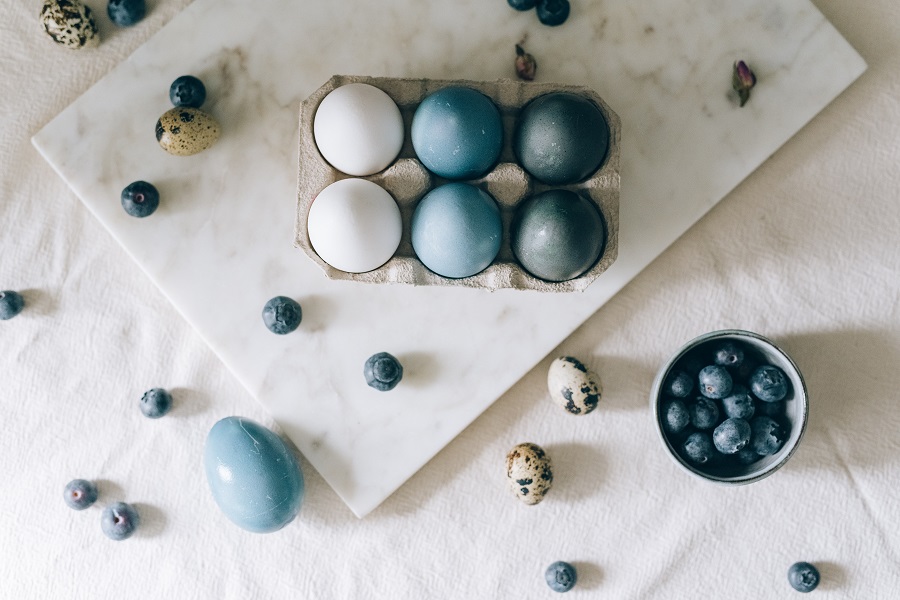 Easter Decorations Overhead View of Dyed Eggs Sitting in a Carton with Other Small Eggs Scattered Around