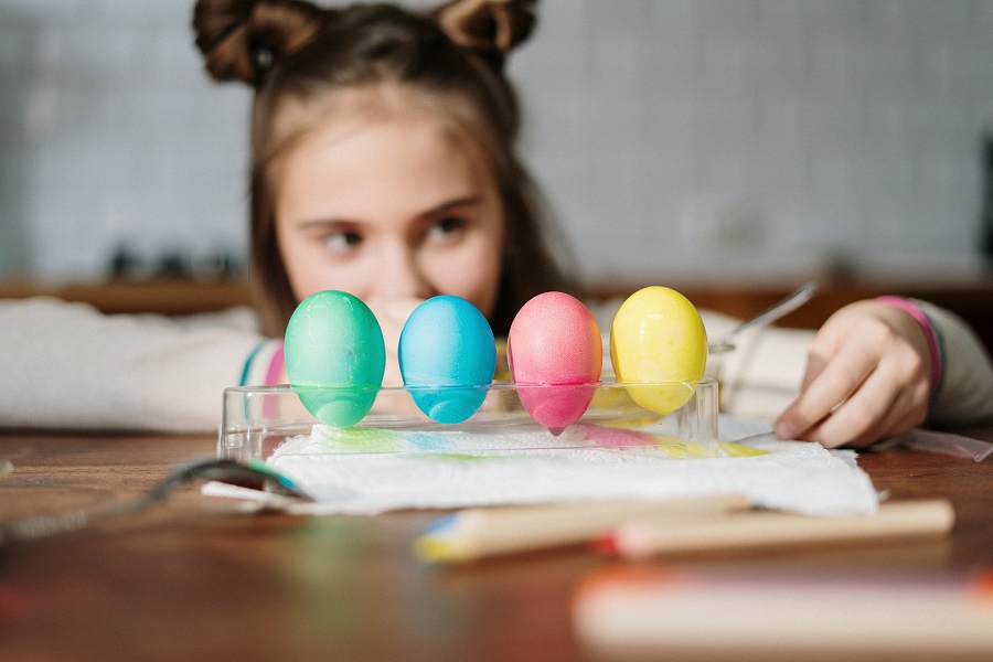 Easter Decorations Little Girl Sitting at a Table Looking at Dyed Eggs